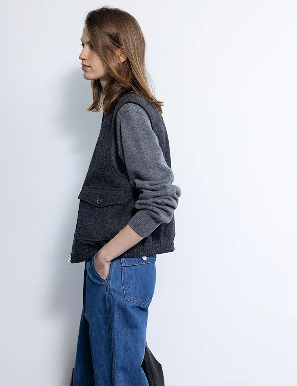 Side view of dark gray wool cashmere polo sweater layered with vest