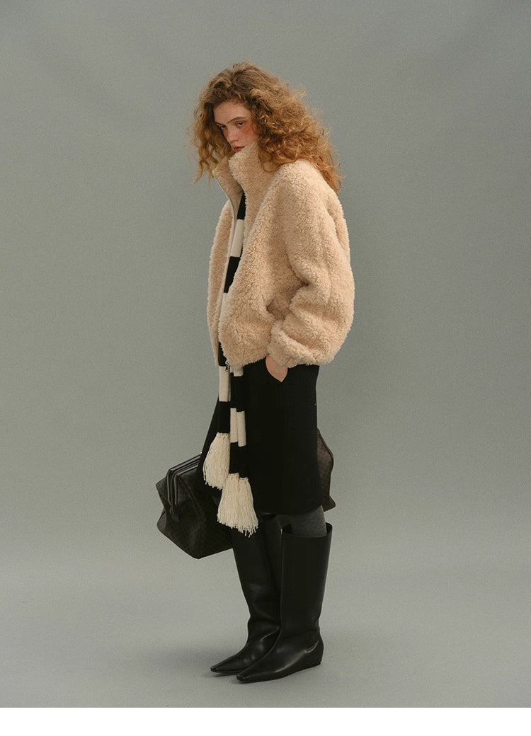 Full side view of cream beige wool high-neck jacket styled with black skirt, scarf and tall boots