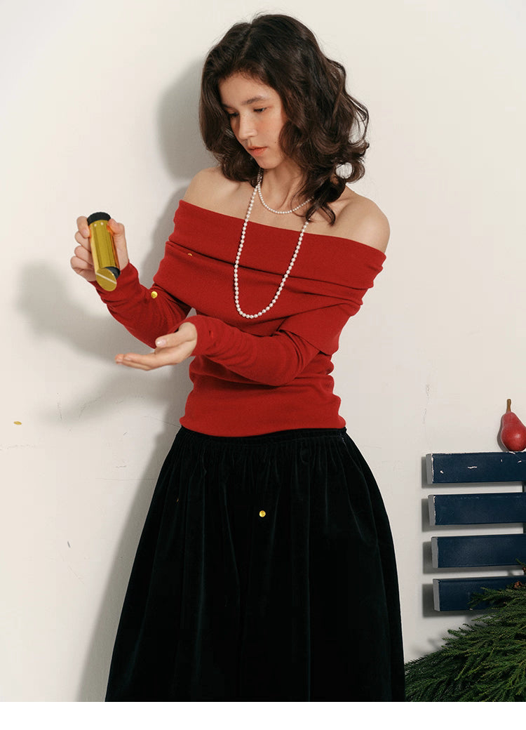 Model wearing holiday-red off-shoulder wool top holding a gold confetti tube