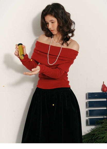 Model wearing holiday-red off-shoulder wool top holding a gold confetti tube