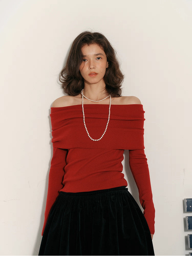 Front view of red off-shoulder draped wool top styled with a black velvet skirt
