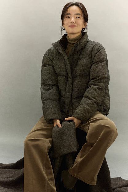 Woman wearing dark taupe wool-blend down jacket sitting with matching scarf.