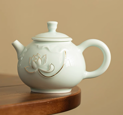 Yingqing Lotus Relief Ceramic Teapot in white side view displaying embossed lotus flower with gold accents placed on a wooden surface